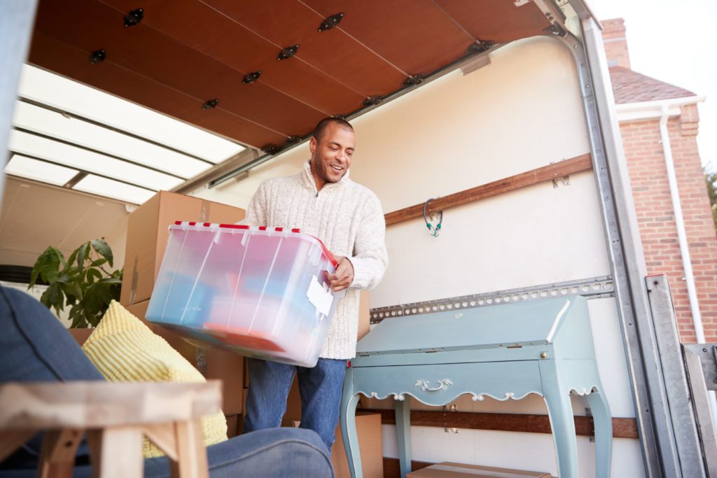 Shop around for a moving company - Man Unloading Furniture From Removal Truck Outside New Home On Moving Day