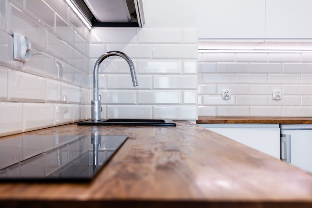 New clean kitchen with wooden table top. 
