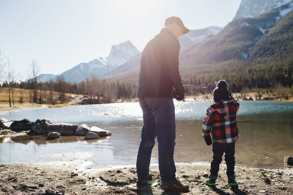 a grandfather and his grandson at a the shore of a lake