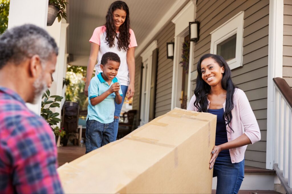 Family with kids of different ages bringing in a moving box